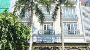 A hotel with a prominent entrance, palm trees, and a sign reading "MACALLAN HOTEL". - MACALLAN HOTEL Phu My Hung- SECC (Ho Chi Minh City)