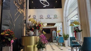 A hotel lobby with a reception desk, large potted plants, and a check-in counter. - MACALLAN HOTEL Phu My Hung- SECC (Ho Chi Minh City)