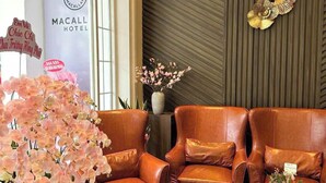 A modern hotel lobby with leather sofas, a geometric coffee table, and decorative wall art. - MACALLAN HOTEL Phu My Hung- SECC (Ho Chi Minh City)