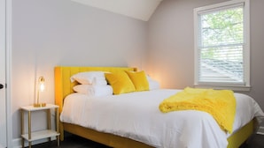 A bedroom with a bed, bedside table, lamp, and window. - Fayetteville Elite Escape – Close to Base & VA Hospitals (Fayetteville)