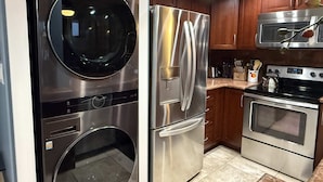 A kitchen with stainless steel appliances, including a refrigerator, oven, microwave, and washing machine. - Whale Watching Oceanfront Escape Molokai Views Cool Tropical Breezes (Lahaina)