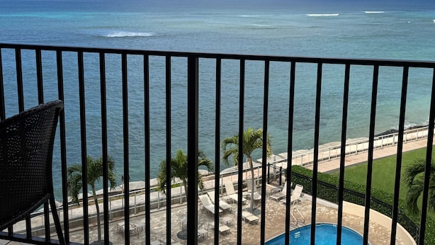 A balcony with a view of the ocean, a pool, and a lounge area with chairs and tables. - Whale Watching Oceanfront Escape Molokai Views Cool Tropical Breezes (Lahaina)