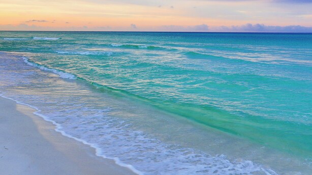 A beach with clear turquoise waters and a calm sea.