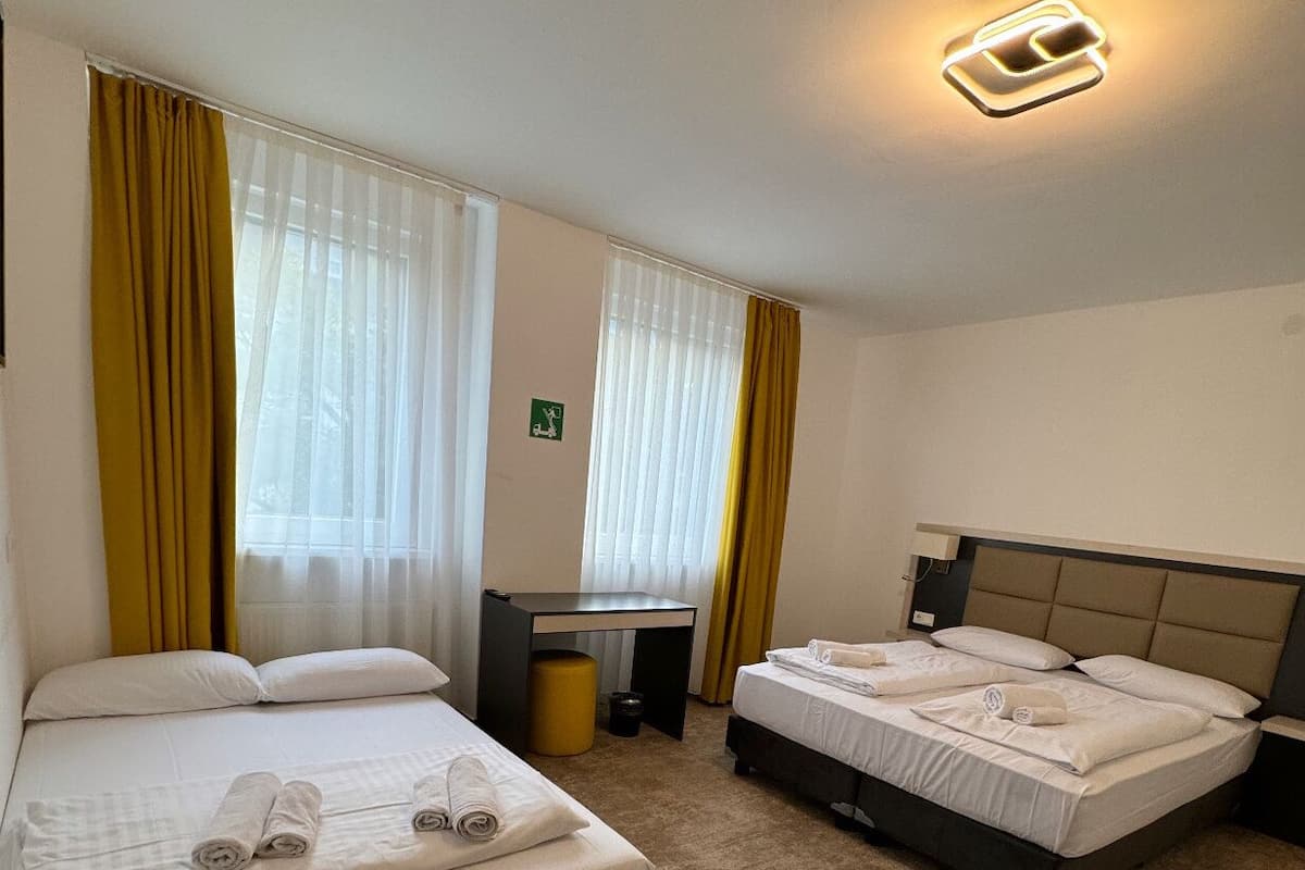 A hotel room with two beds, a desk, and a small table.