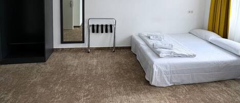 Una habitación de hotel con cama, armario, espejo, televisor y radiador.