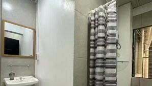 A bathroom with a sink, mirror, and shower curtain. - Quaint Downtown Loft/WI-FI (San José)