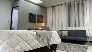 A hotel room with a bed, a sofa, a lamp, and two paintings on the wall. - Quaint Downtown Loft/WI-FI (San José)