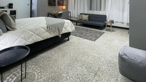 A modern hotel room with a large bed, a sofa, a desk, and a television. - Quaint Downtown Loft/WI-FI (San José)