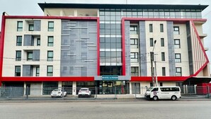 A modern hotel building with a prominent red and white facade, multiple balconies, and a sign indicating it is the Hotel La Pivoine. - Hôtel La Pivoine (Abidjan)