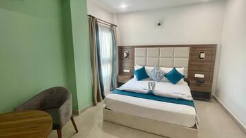 A neatly arranged hotel room with a bed, a chair, and a small table.