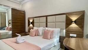 A neatly arranged bedroom with a large bed, a wooden headboard, and bedside lamps. - Hôtel La Pivoine (Abidjan)