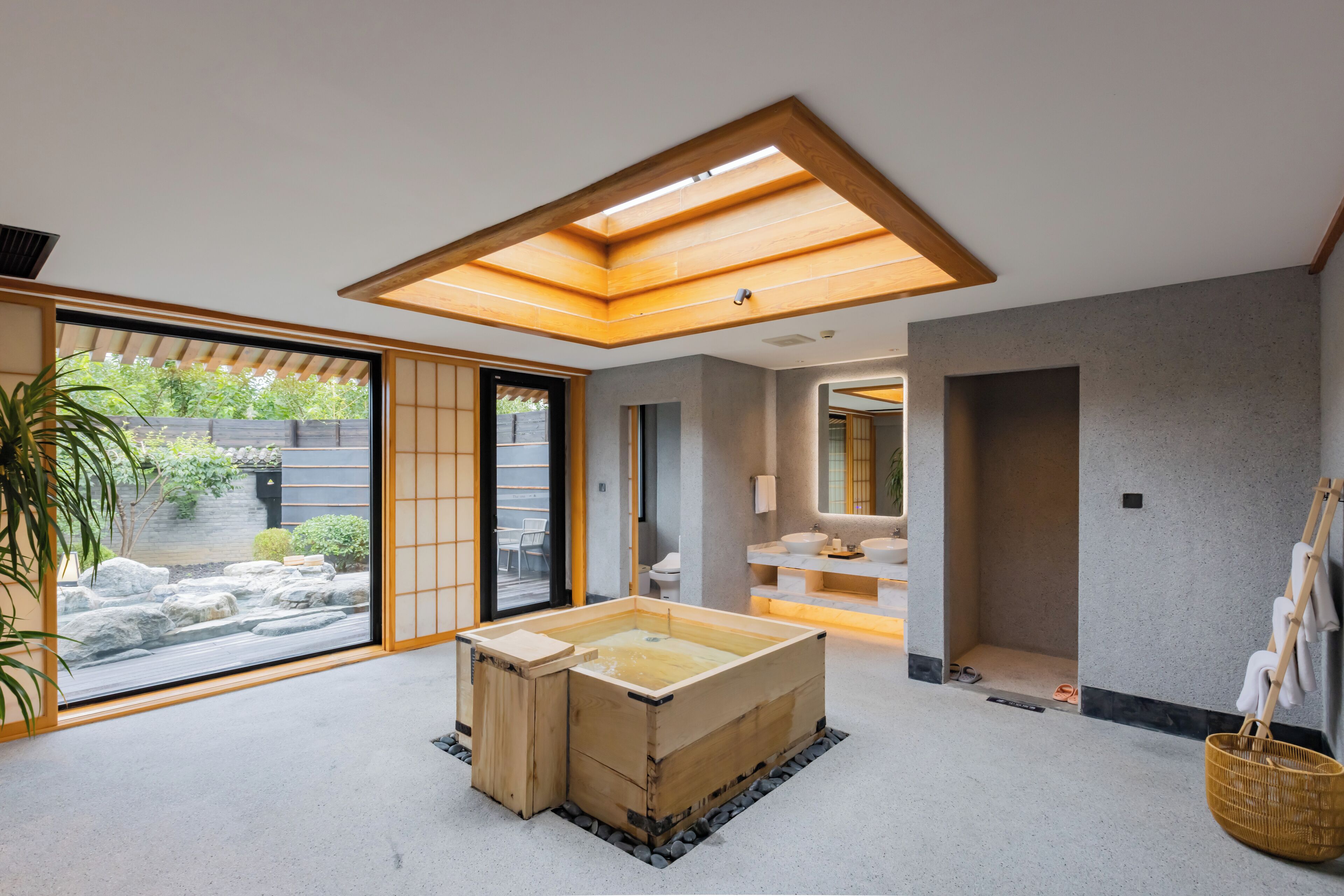 A modern interior with a wooden bathtub, a large window, and a view of a garden.