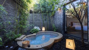 A spa area with a hot tub surrounded by bamboo, a stone bench, and a lantern. - Beijing XiaoTang YiPiao Hot Spring Resort (Changping)