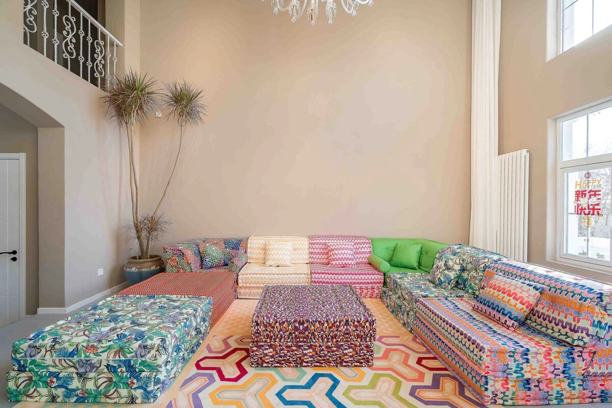 A spacious living area with a large sofa set, a patterned rug, and a potted plant.