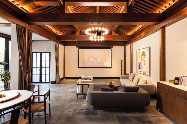 A modern living room with a sofa, a coffee table, and a dining area with a table and chairs. - Beijing XiaoTang YiPiao Hot Spring Resort (Changping)