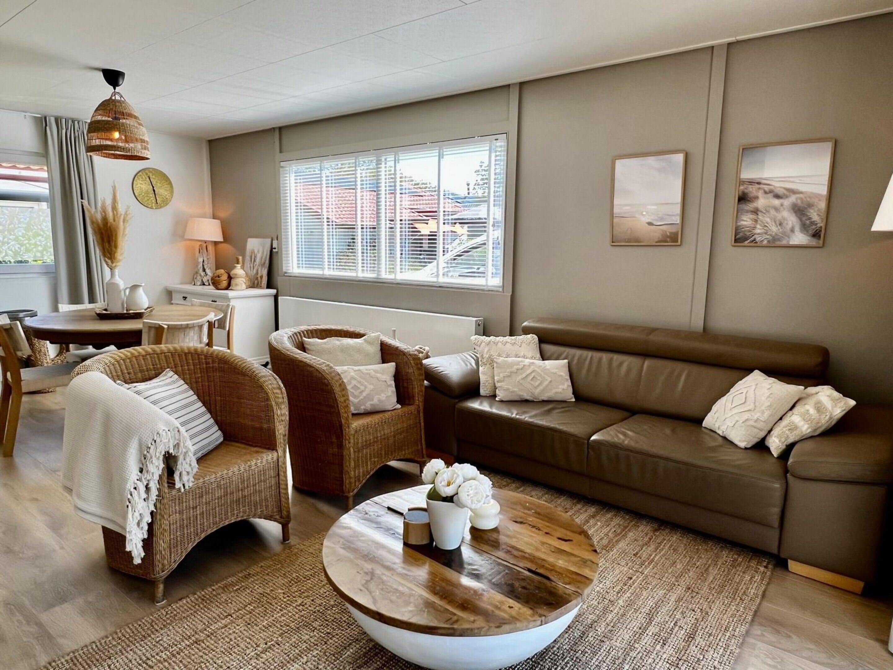 A modern living room with wicker furniture, a brown leather sofa, and a round coffee table.