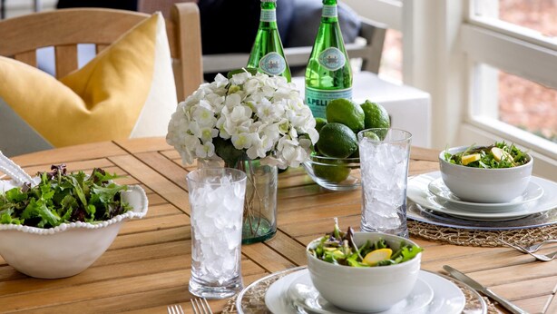 A dining table set with a salad, two bottles of water, and a vase of flowers. - Luxe interiors, pet-friendly & fireplace on the porch (Bluffton)