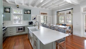 A spacious kitchen with a large island, wooden floors, and light blue cabinetry. - Luxe interiors, pet-friendly & fireplace on the porch (Bluffton)