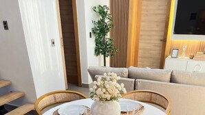 Une table de salle à manger ronde, avec des sets de table blancs et un vase de fleurs placé au centre.