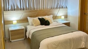 Une chambre à coucher avec un grand lit, deux tables de chevet, une tête de lit et un luminaire suspendu.