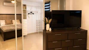 Ein Schlafzimmer mit Bett, Schminktisch, Fernseher, Kleiderschrank und Deckenventilator.