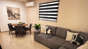 Ein modernes Wohnzimmer mit einem grauen Sofa, einem runden Esstisch und einem Deckenventilator.