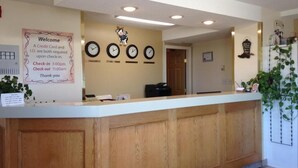 A reception desk with a clock, a welcome sign, and a plant.