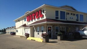 A motel with a prominent red sign, a stone facade, and a parking lot.
