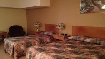 Habitación de hotel con dos camas, una silla, una mesita de noche y un cuadro en la pared.