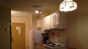 A compact kitchen with white cabinets, a stove, and a refrigerator.