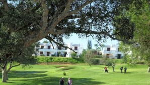 Campo de golf con una mesa lista para el desayuno, rodeado de árboles y con vistas a un club de campo.