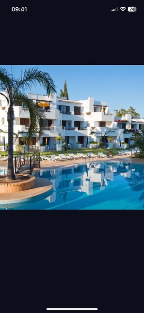 Un hôtel doté d'une piscine, de plusieurs balcons et d'espaces extérieurs aménagés pour se détendre.