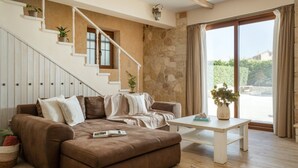Un salon avec un canapé marron, une table basse blanche et un escalier agrémenté de plantes en pot.