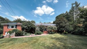 A two-story brick house with a small front yard, a solar panel on the roof, and a well-maintained lawn. - Charming 1-bedroom apartment in fabulous Princeton with WiFi, AC (Princeton)