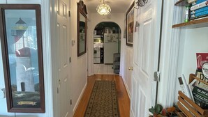 A hallway with a patterned rug, a wooden bench with books, and a door leading to a kitchen. - Charming 1-bedroom apartment in fabulous Princeton with WiFi, AC (Princeton)