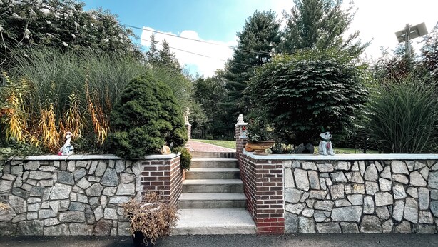 A stone wall entrance with steps leading to a brick pathway, surrounded by various plants and trees. - Charming 1-bedroom apartment in fabulous Princeton with WiFi, AC (Princeton)