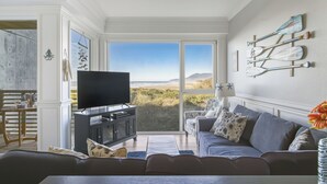 Una sala de estar con un gran ventanal, un televisor de pantalla plana, un sofá y decoración en las paredes.