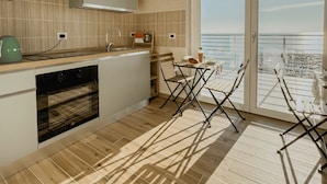Una cocina moderna con un amplio ventanal con vistas al mar, un comedor con mesa y sillas, y vistas del océano.
