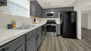 A modern kitchen with grey cabinets, stainless steel appliances, and a wooden floor. - Central Downtown 3BR with Workspaces Near NRG, Zoo, TSU & Medical Center (Houston)