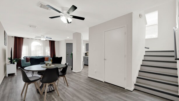 A modern living room with a dining area, a staircase, and a kitchen in the background. - Central Downtown 3BR with Workspaces Near NRG, Zoo, TSU & Medical Center (Houston)