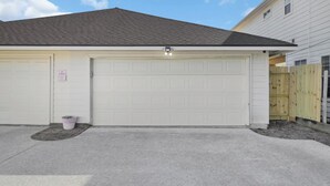 A garage with a 'NO PARKING' sign, a light fixture above the garage door, and a wooden fence in the background. - Central Downtown 3BR with Workspaces Near NRG, Zoo, TSU & Medical Center (Houston)