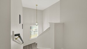 A staircase with white walls and a wooden handrail. - Central Downtown 3BR with Workspaces Near NRG, Zoo, TSU & Medical Center (Houston)