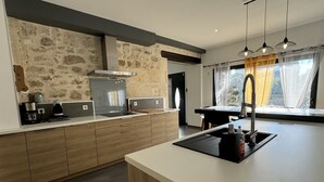 A modern kitchen with a central island, built-in appliances, and a stone accent wall.
