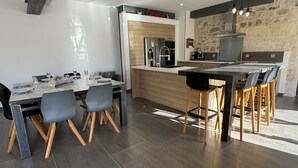 A modern kitchen with a central island, wooden chairs, and a dining table set for four.