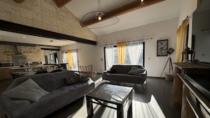 A modern living room with a sofa, a coffee table, and a dining area with a kitchen in the background.
