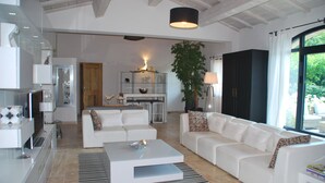 Een moderne woonkamer met een witte bank, een salontafel en een grote plant.