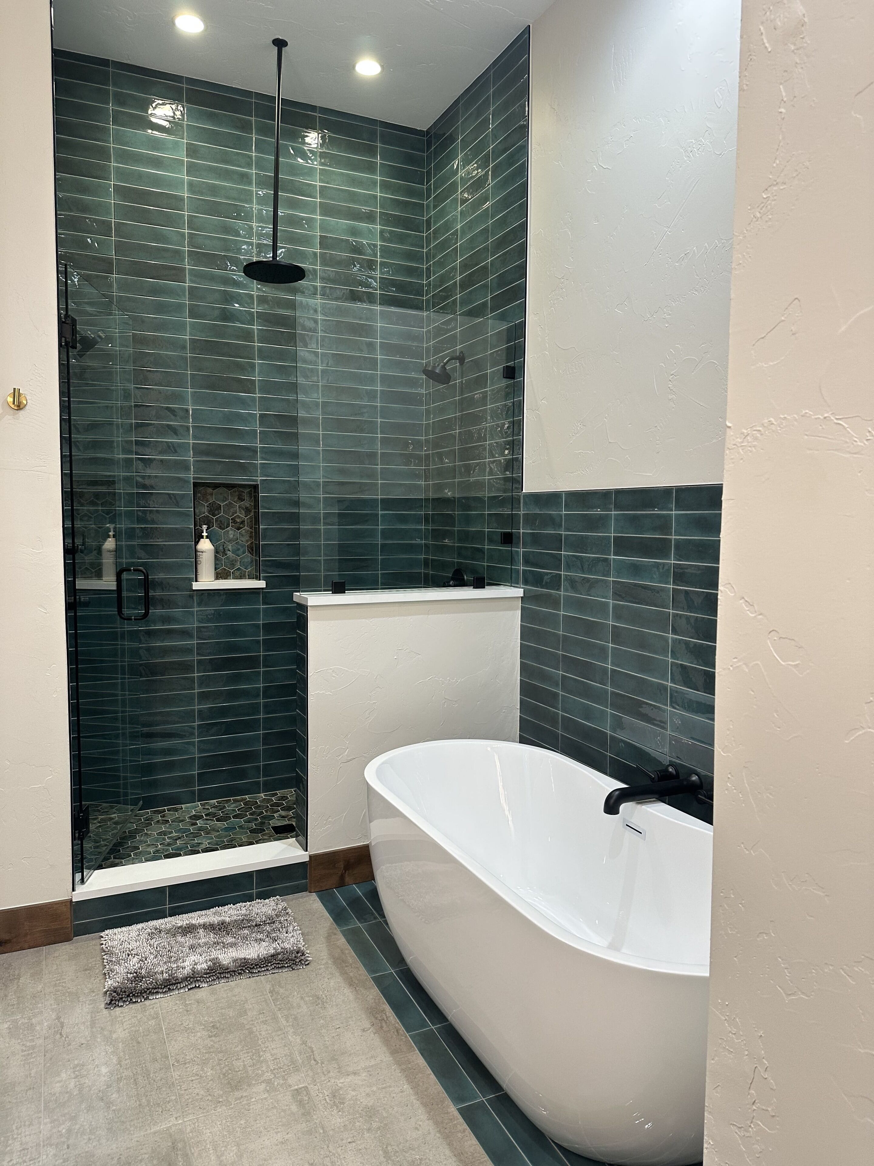 A modern bathroom with a freestanding bathtub, a glass-enclosed shower, and a tiled wall.