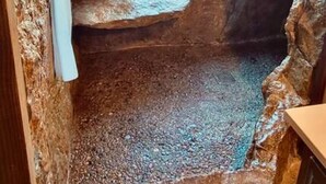 Un interior rústico de piedra con una ventana que ofrece vistas a un campo cubierto de hierba.
