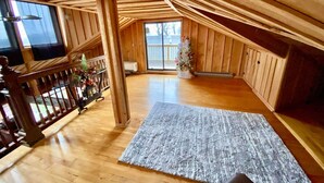 A spacious attic room with wooden walls and a wooden floor. - Penthouse w/ Boho Loft, Jacuzzi, + Balcony -3 BR (Saint Joseph)