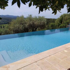 A clear blue infinity pool with a view of green trees and distant hills. - Luxury villa - air-conditioned - pool - sleeps 14, 7 bedrooms and 7 bathrooms, 11 beds (Sanary-sur-Mer)